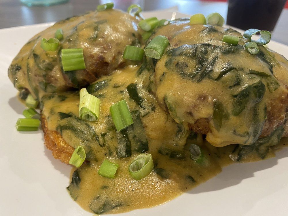 Fried food with creamy spinach sauce, garnished with chopped green onions.