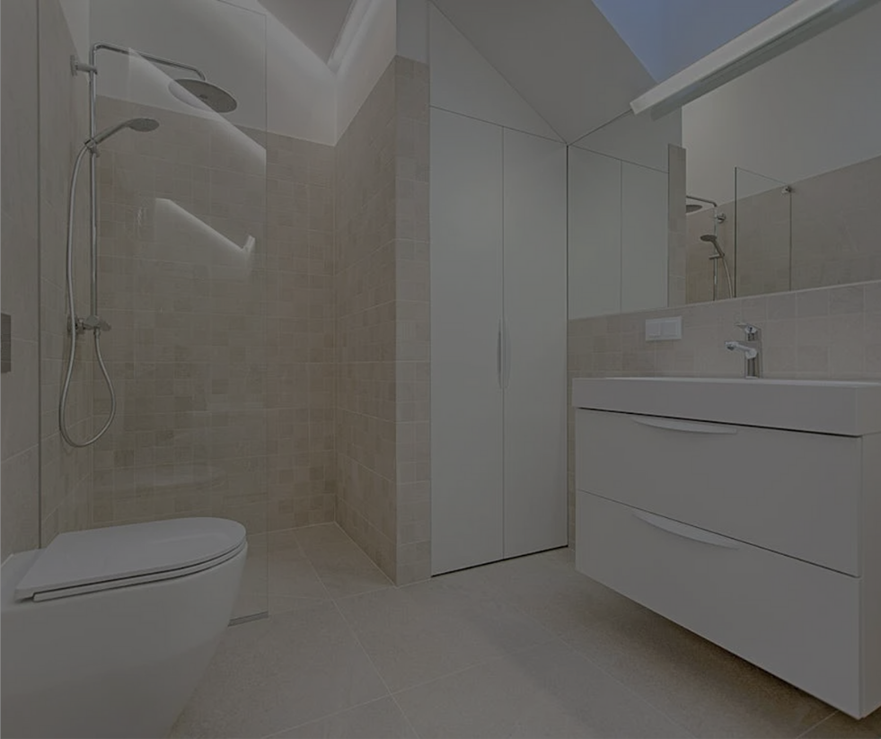 Modern bathroom with walk-in shower, white vanity, and toilet. Beige tiled walls and floor, white cabinets.