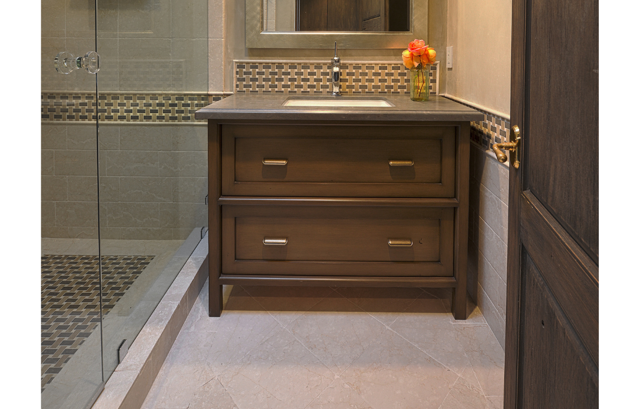 Brown bathroom vanity with a sink, two drawers, and a floral vase.