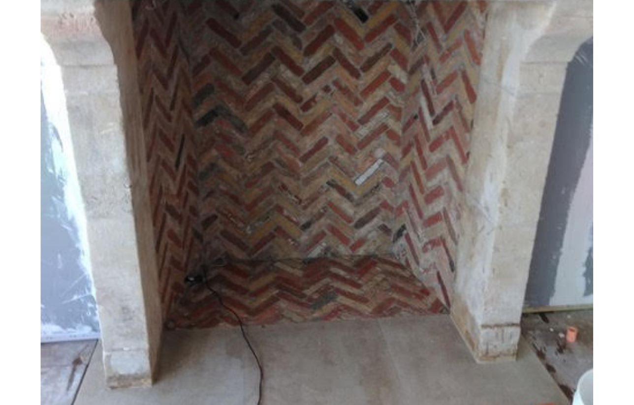 Brick fireplace interior with a herringbone pattern, framed by concrete.