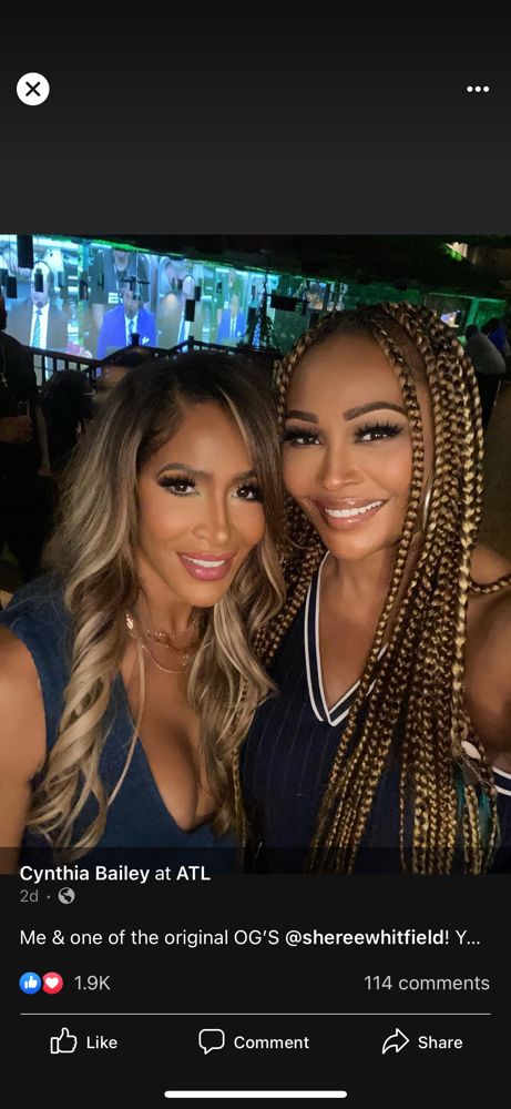 Two women smiling at a neon-lit night venue, posing closely together.