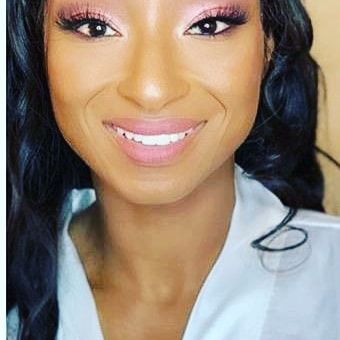 Close-up portrait of a smiling woman in a white top with pink eye makeup and dark braided hair