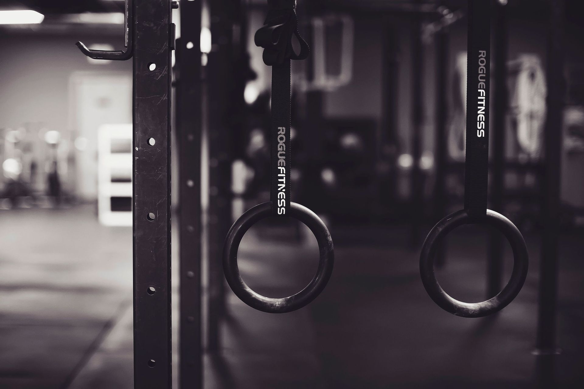 Two gymnastic rings are hanging from a rack in a gym.