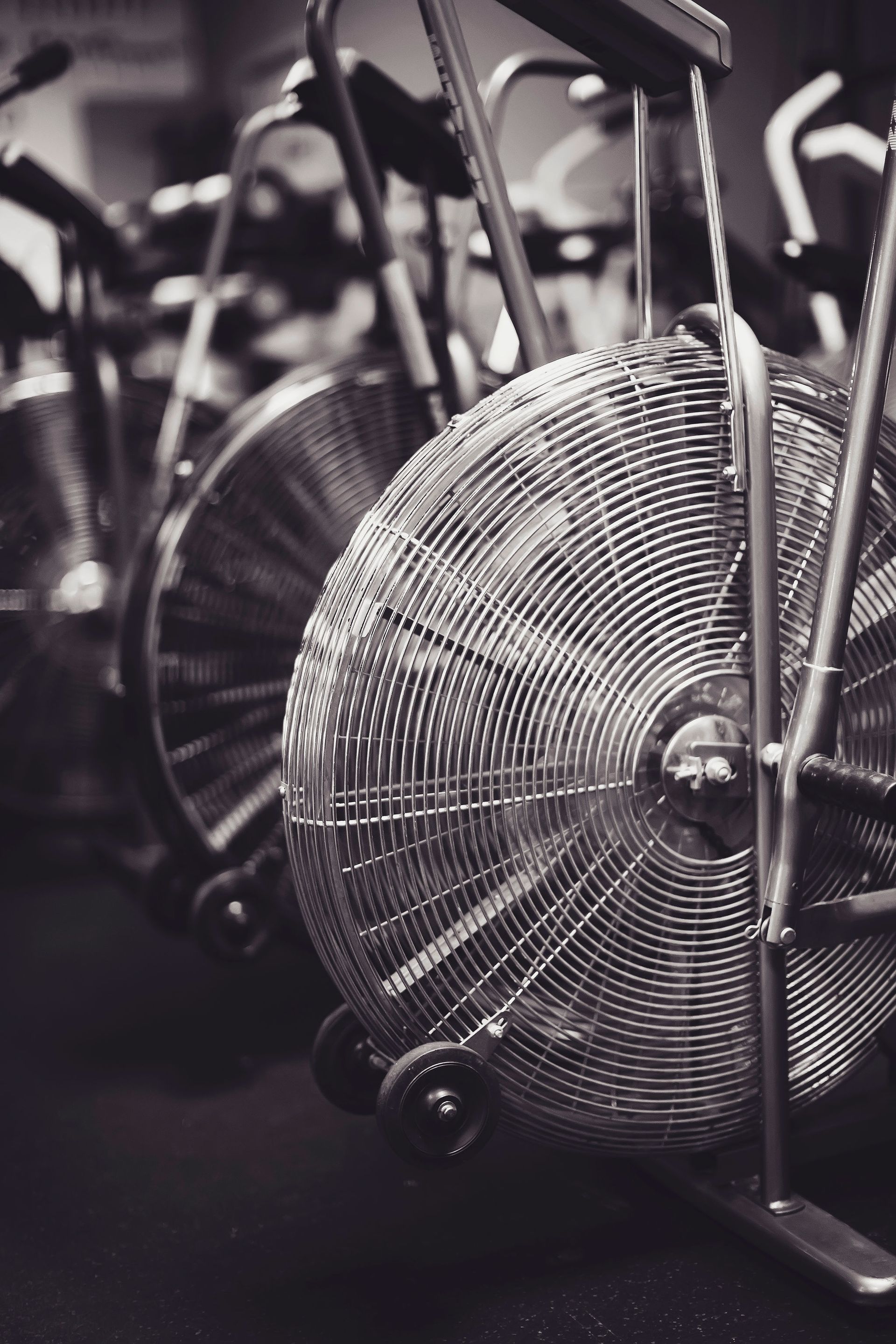 A black and white photo of an air bike in a gym.