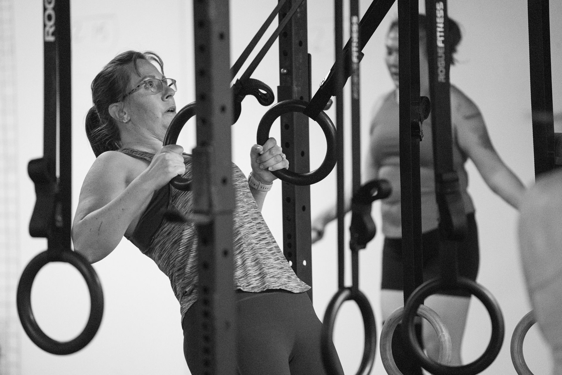A woman is doing pull ups on gymnastic rings in a gym
