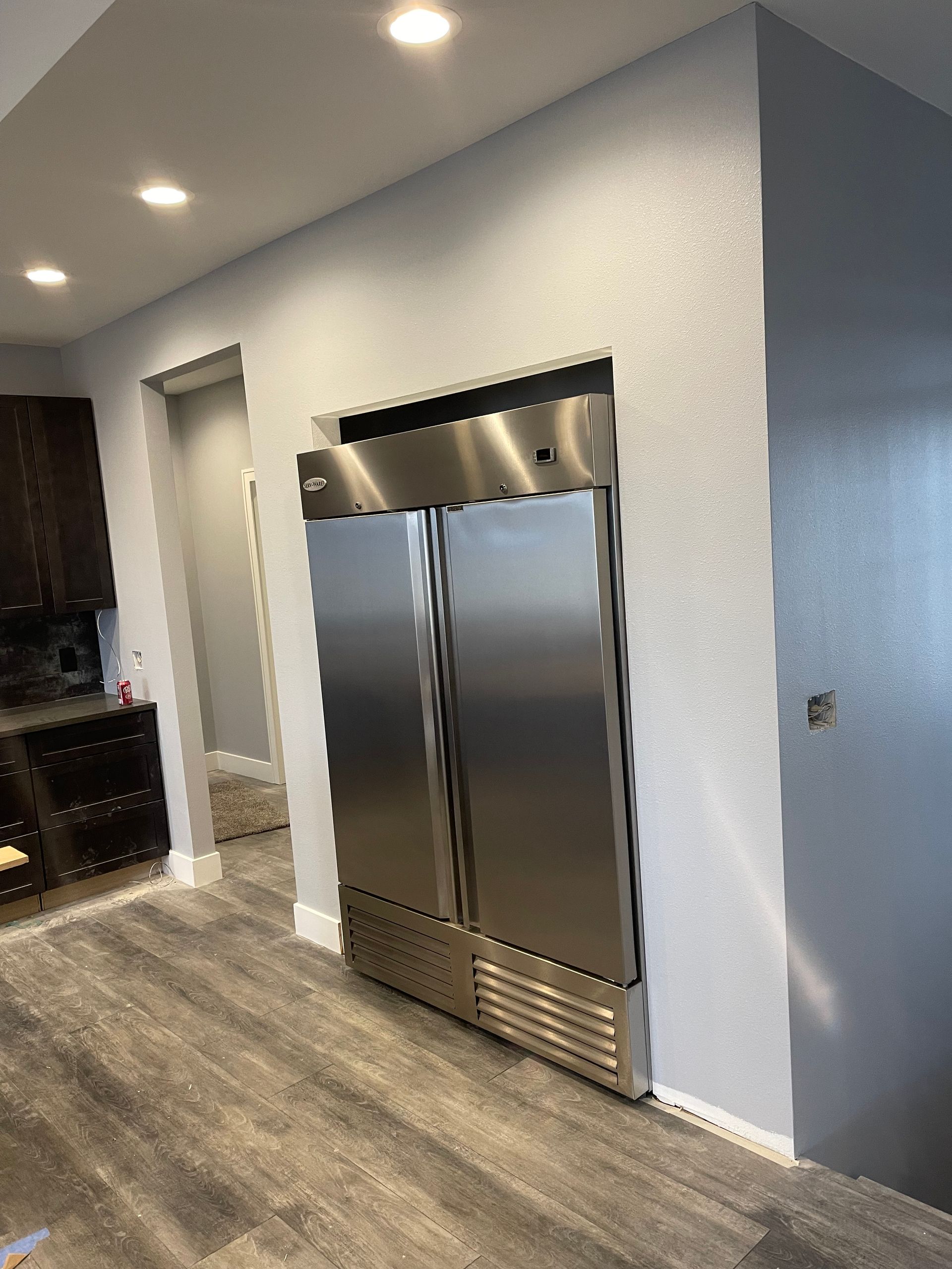 A stainless steel ice maker is filled with ice and a scoop.