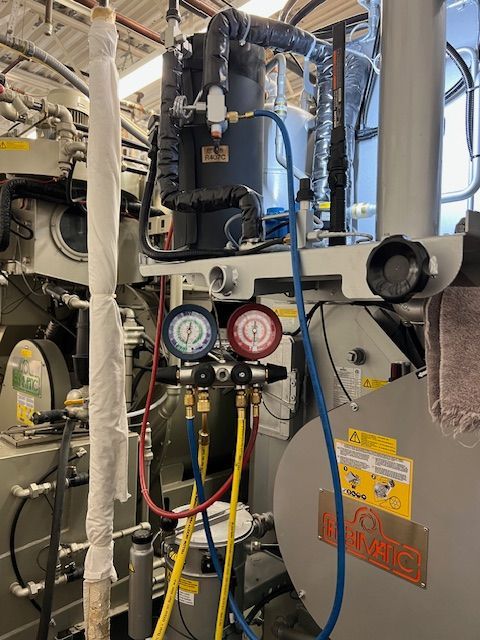 A man is fixing a refrigerator with a screwdriver.