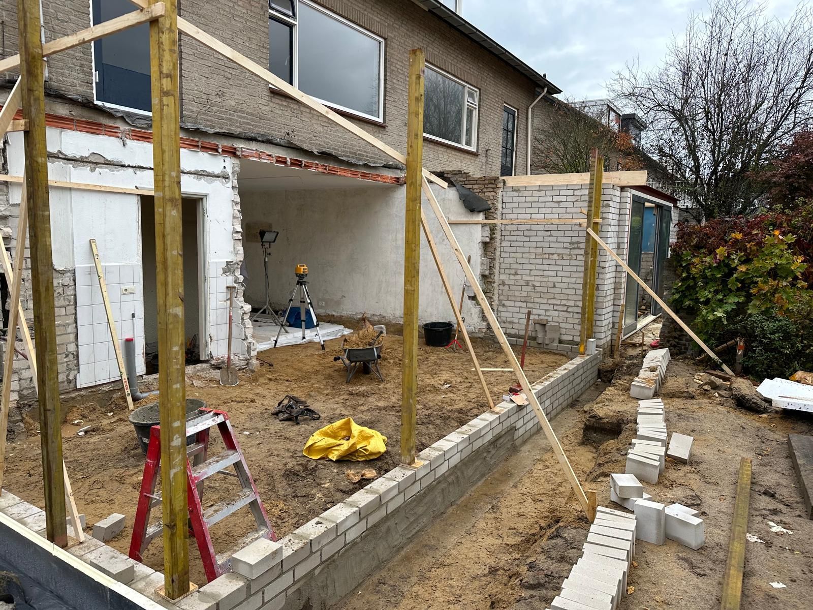 Er wordt een huis verbouwd en er wordt een bakstenen muur gebouwd.