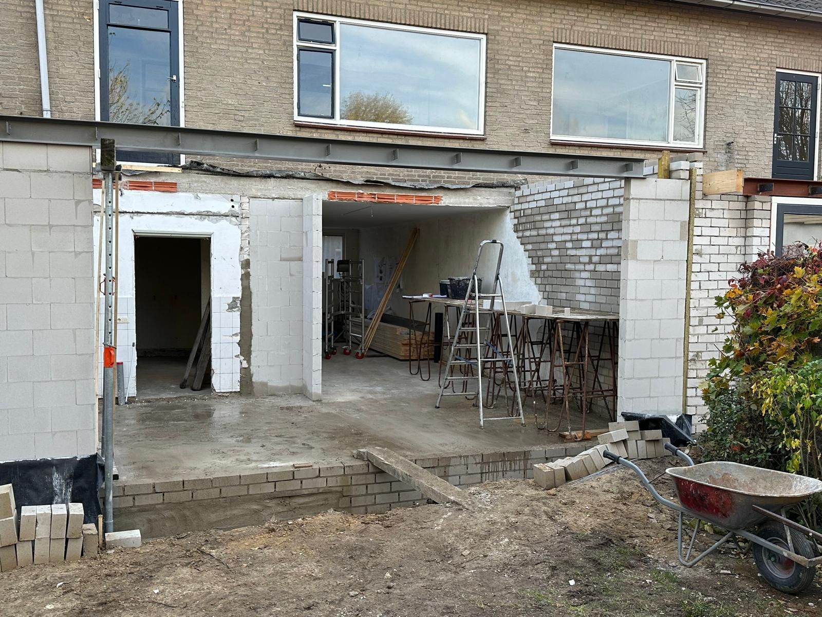 Een huis in aanbouw met een kruiwagen ervoor.