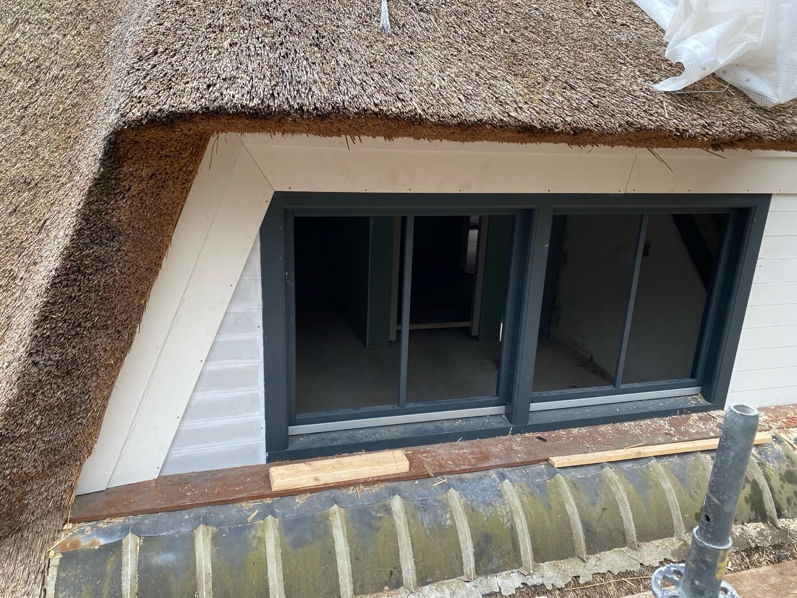 Een rieten dak met daaronder een raam.