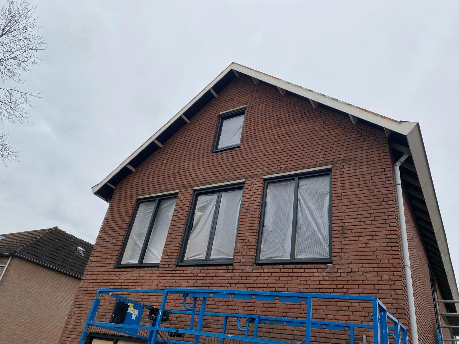 Een bakstenen huis met een blauwe lift ervoor.