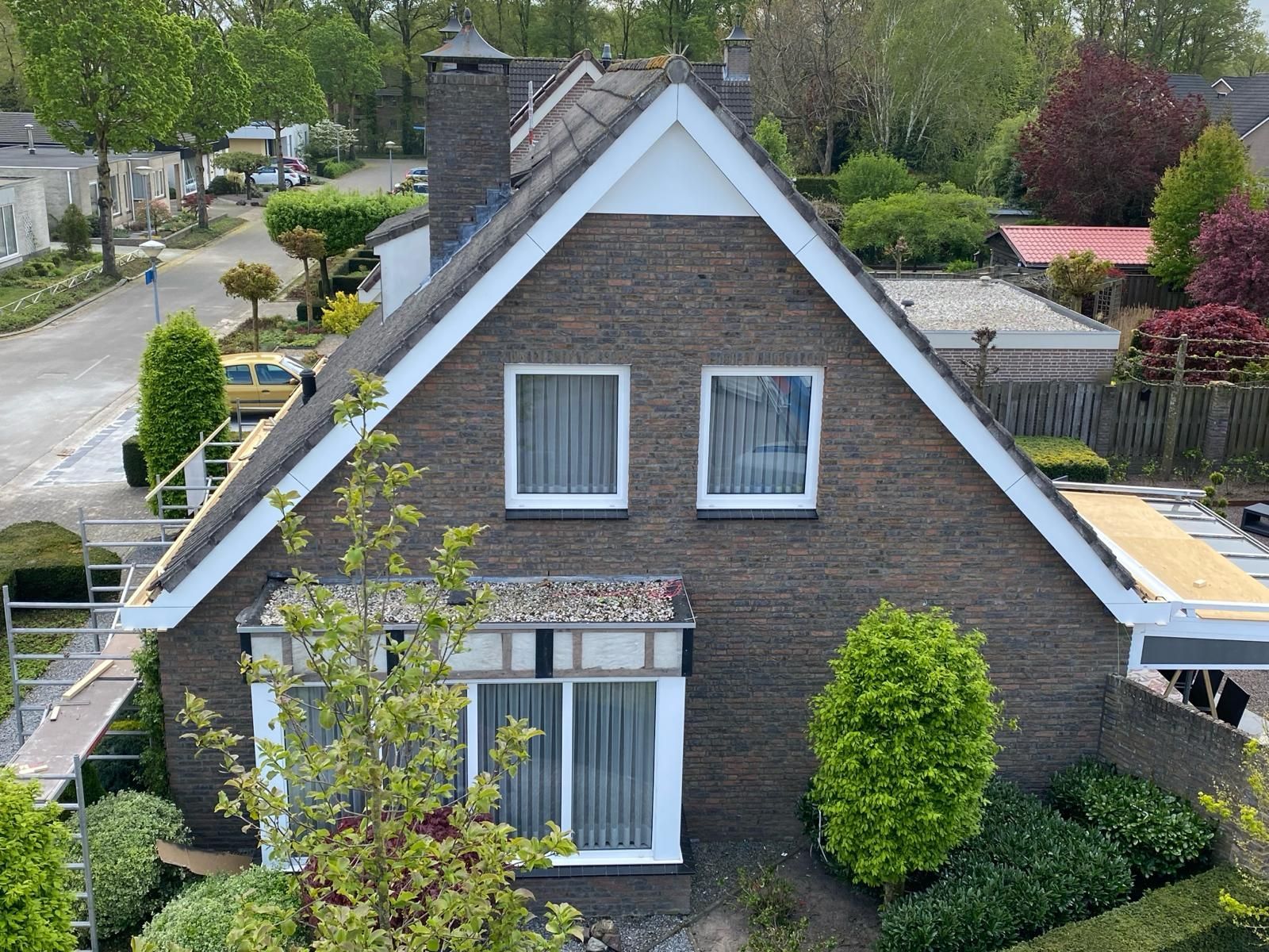 Een luchtfoto van een bakstenen huis met een witte rand op het dak