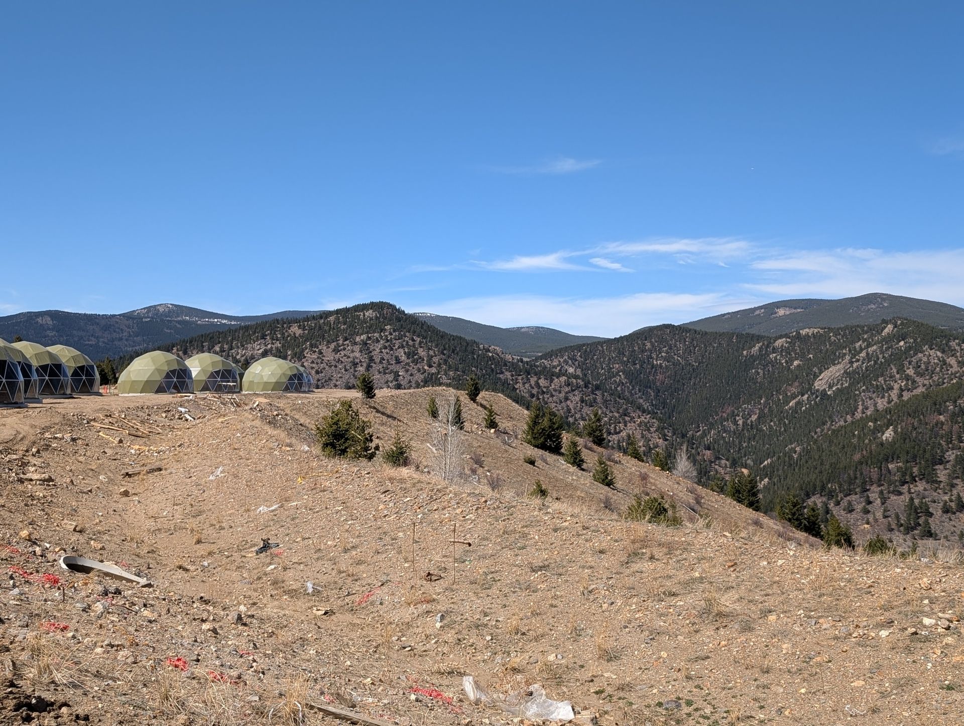 A group of tents are sitting on top of a hill in the mountains.