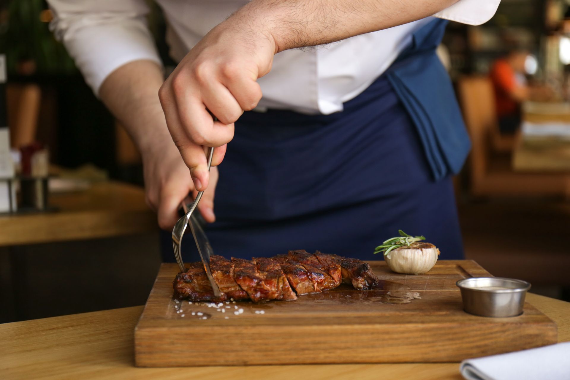A man is cutting a piece of meat on a cutting board.