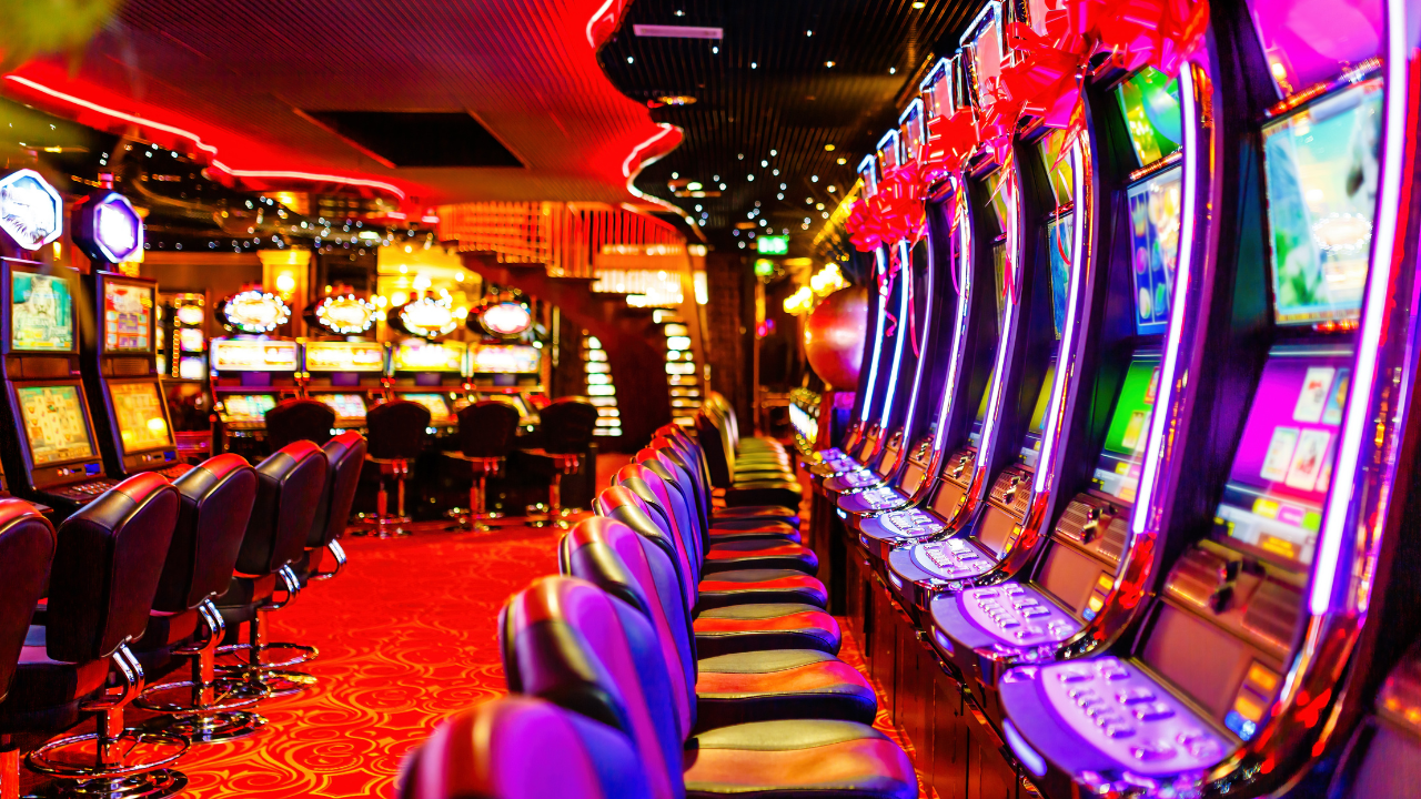 A row of slot machines in a casino with purple chairs.