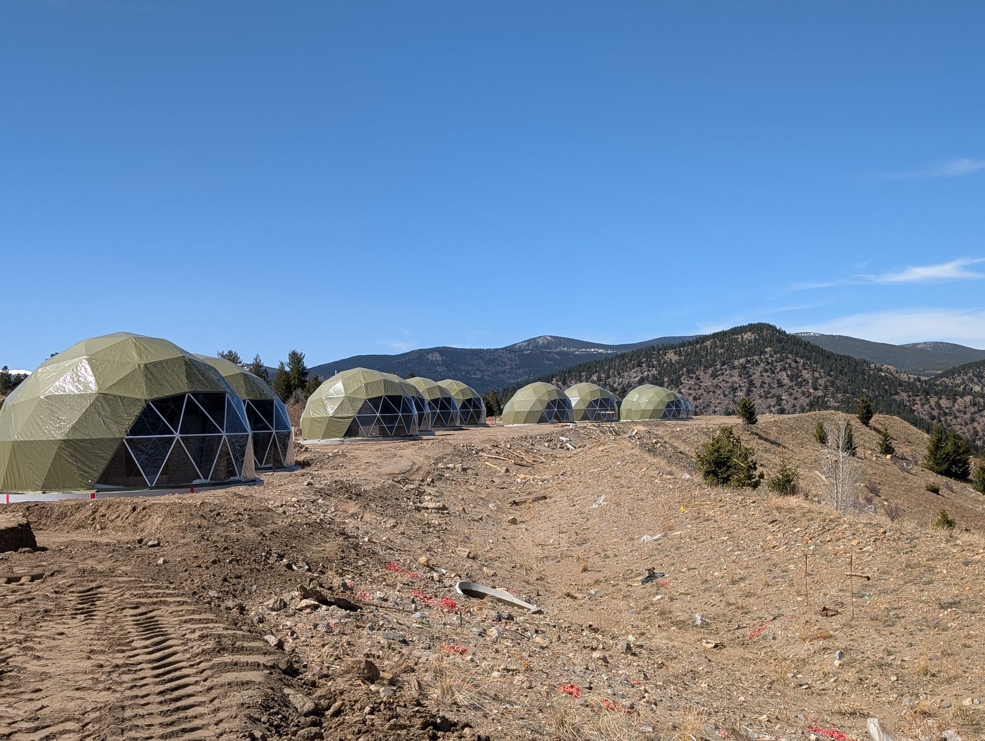 A row of dome tents are sitting on top of a dirt hill.