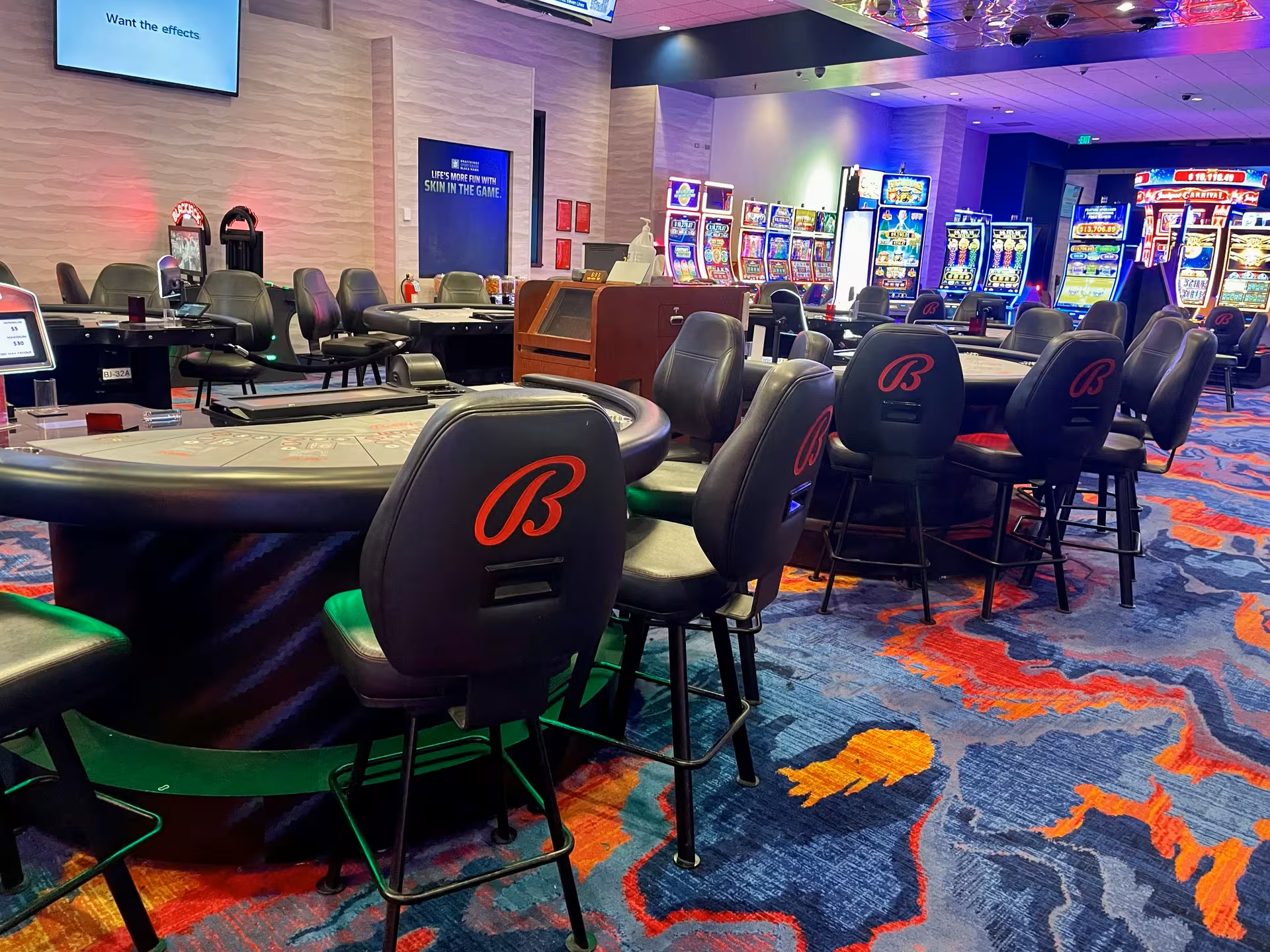 A casino with tables and chairs and a lot of slot machines.
