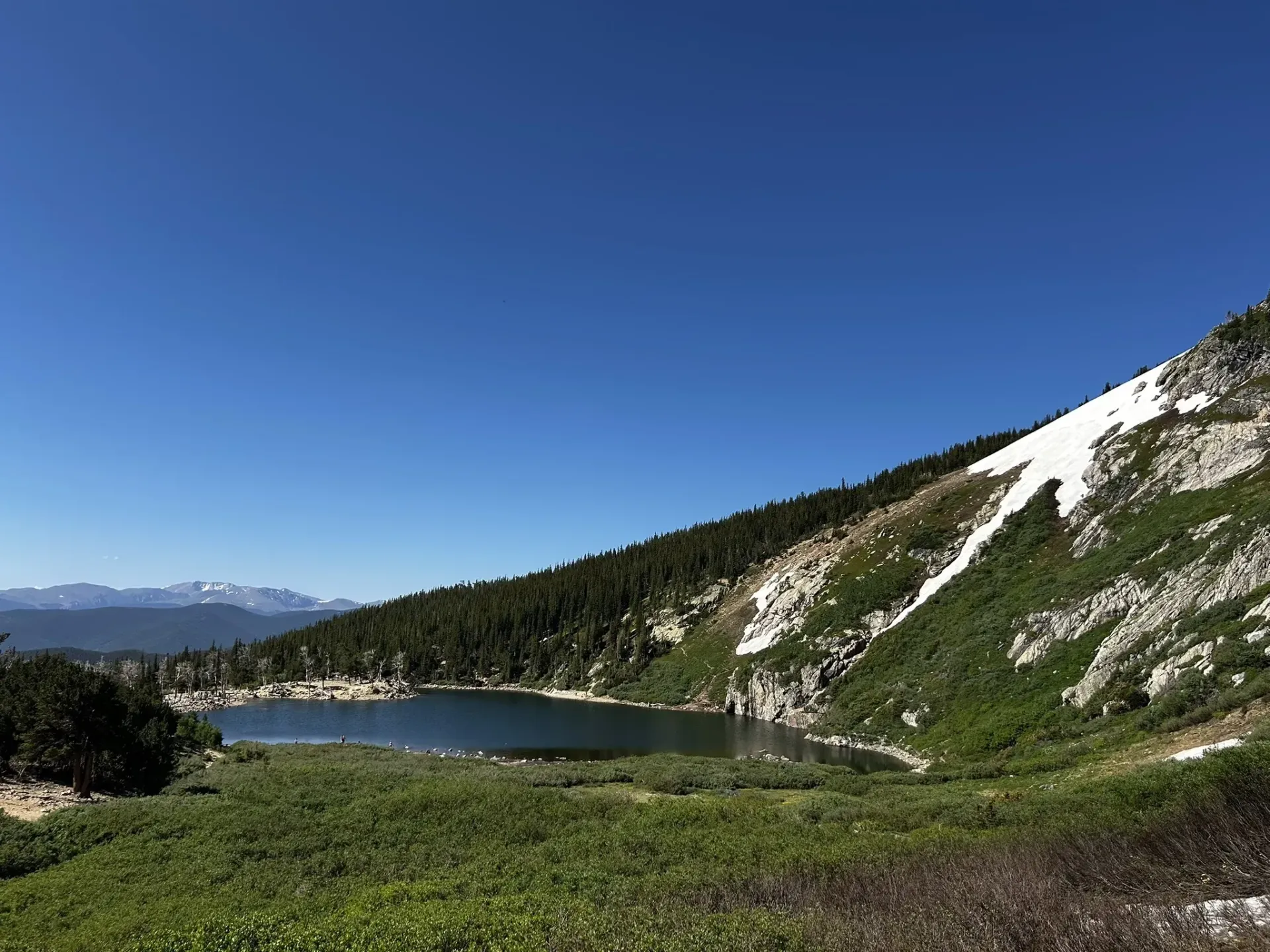 There is a lake in the middle of a mountain surrounded by trees.