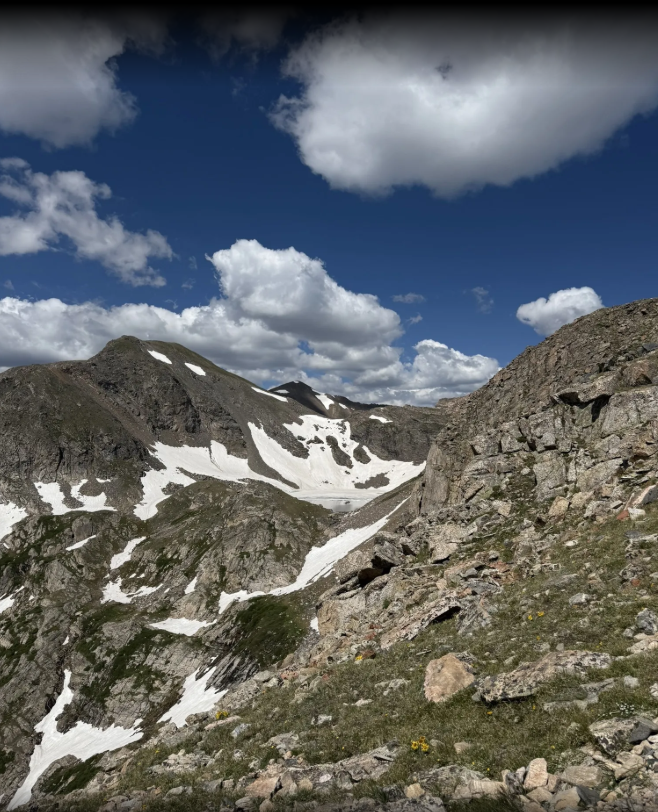 A mountain with snow on it and a blue sky with clouds