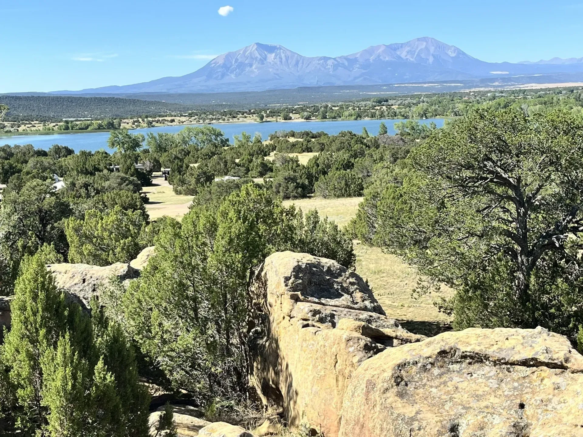 A view of a lake from a rocky cliff with mountains in the background.