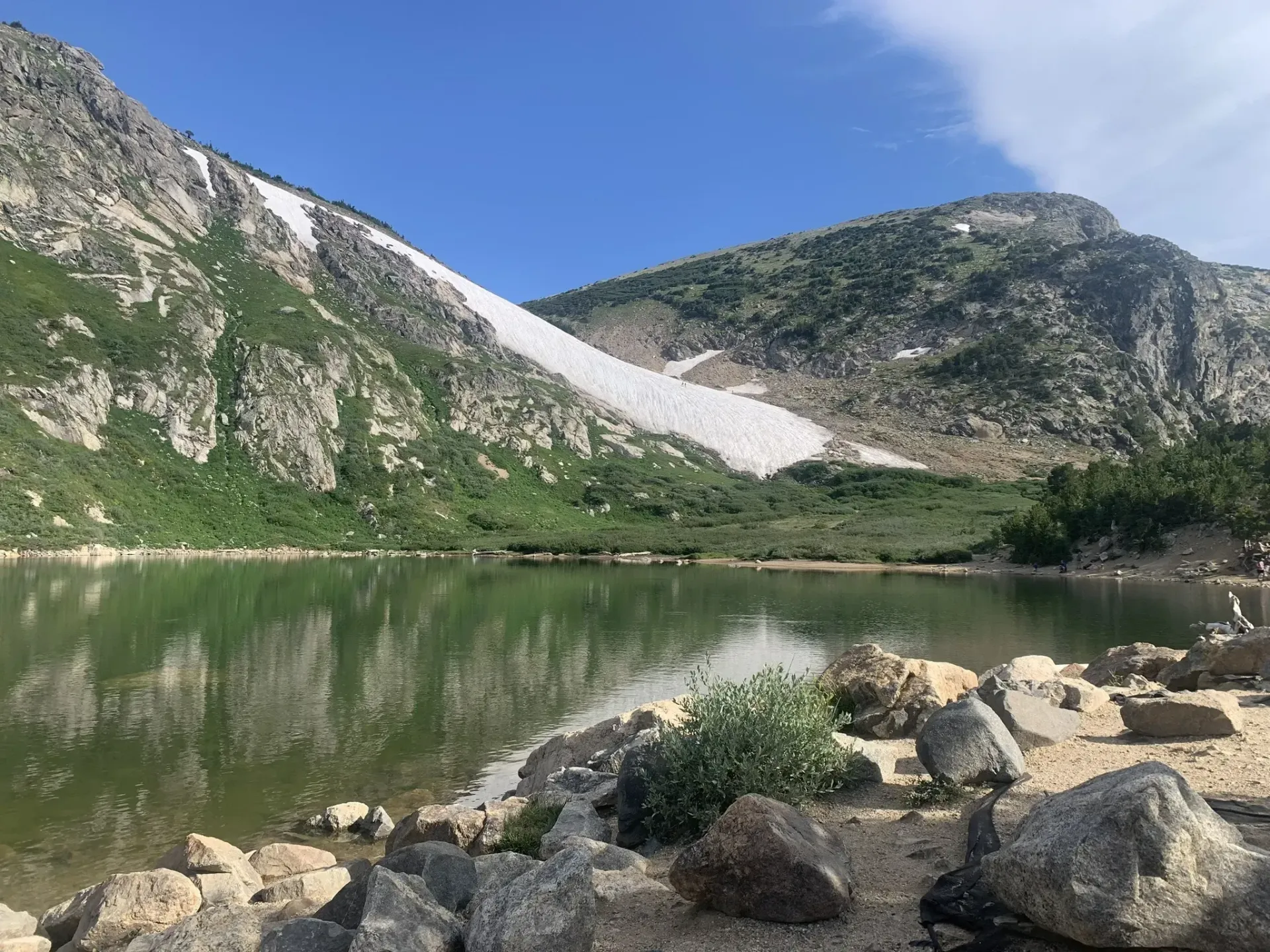 A lake surrounded by rocks and mountains with a mountain in the background.