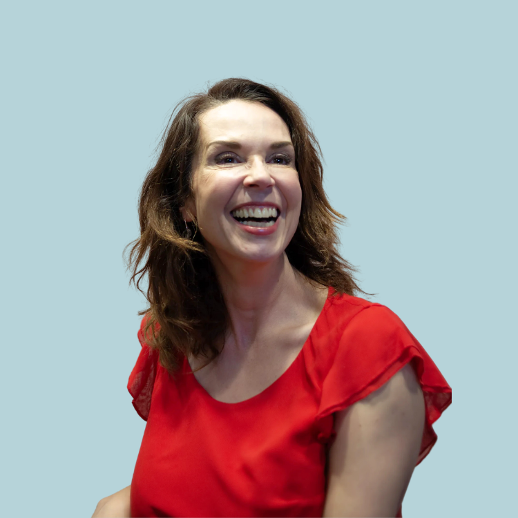 A woman in a red shirt is smiling and looking at the camera