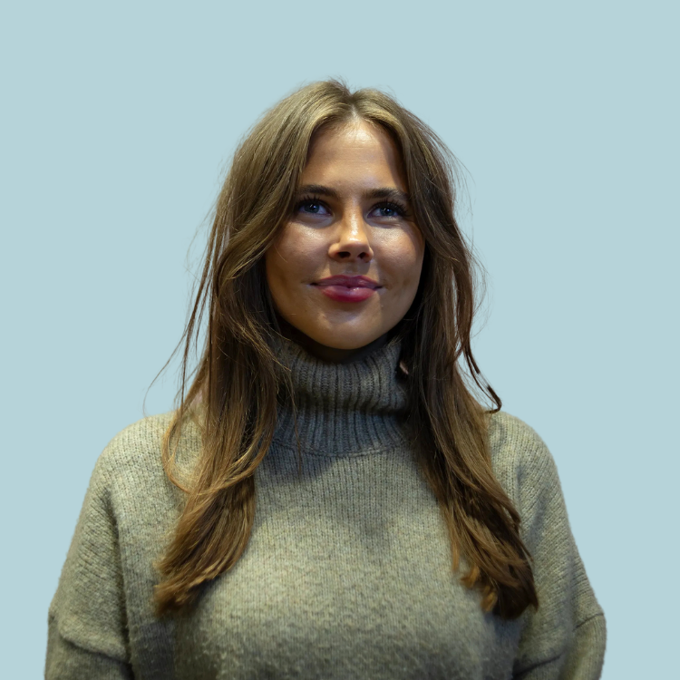 A woman wearing a turtleneck sweater is smiling for the camera