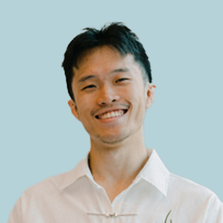 Smiling Asian man in a white shirt against a light blue background.