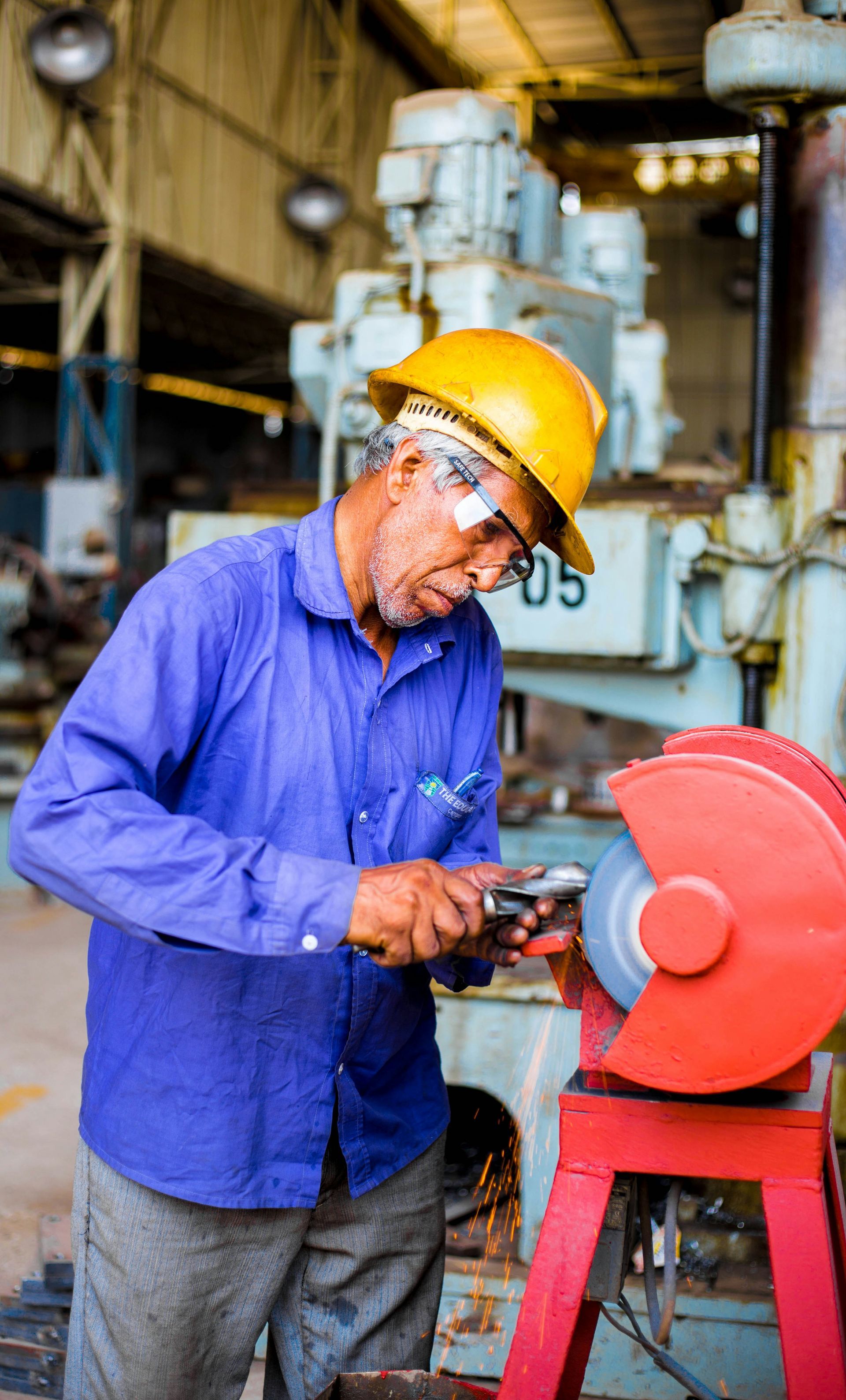 A man wearing a hard hat is working on a machine in a factory.