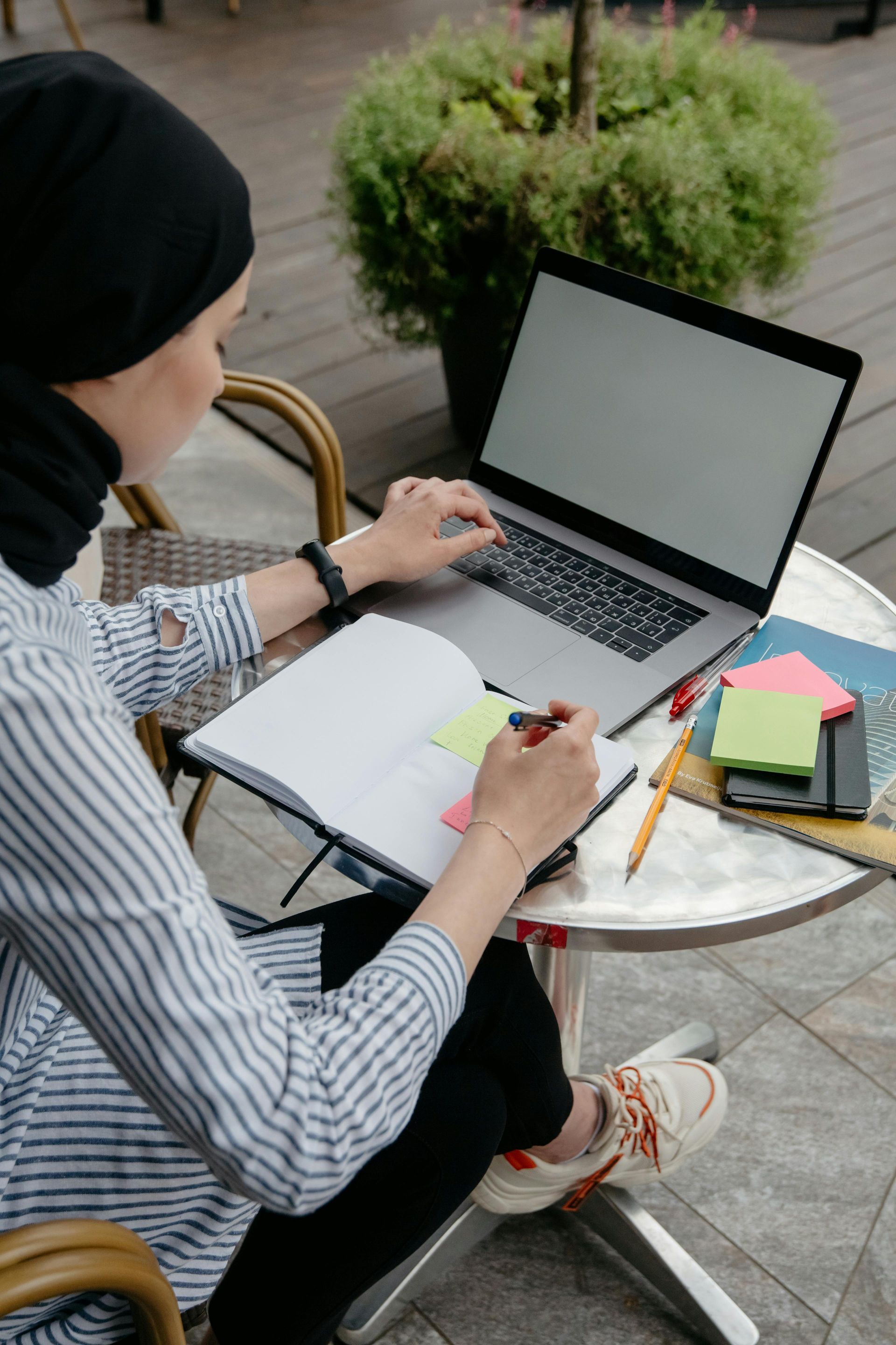 A woman is sitting at a table using a laptop computer.