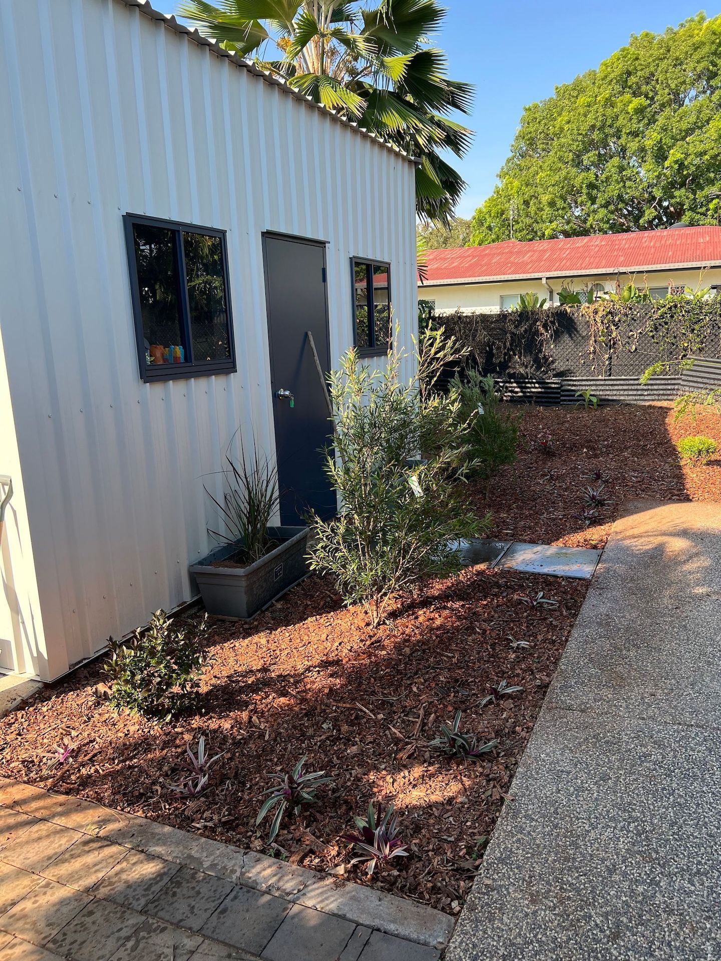 Person Walking on Grass, Near a Hedge and a Gray House on a Sunny Day — Green Scene NT in Darwin, NT