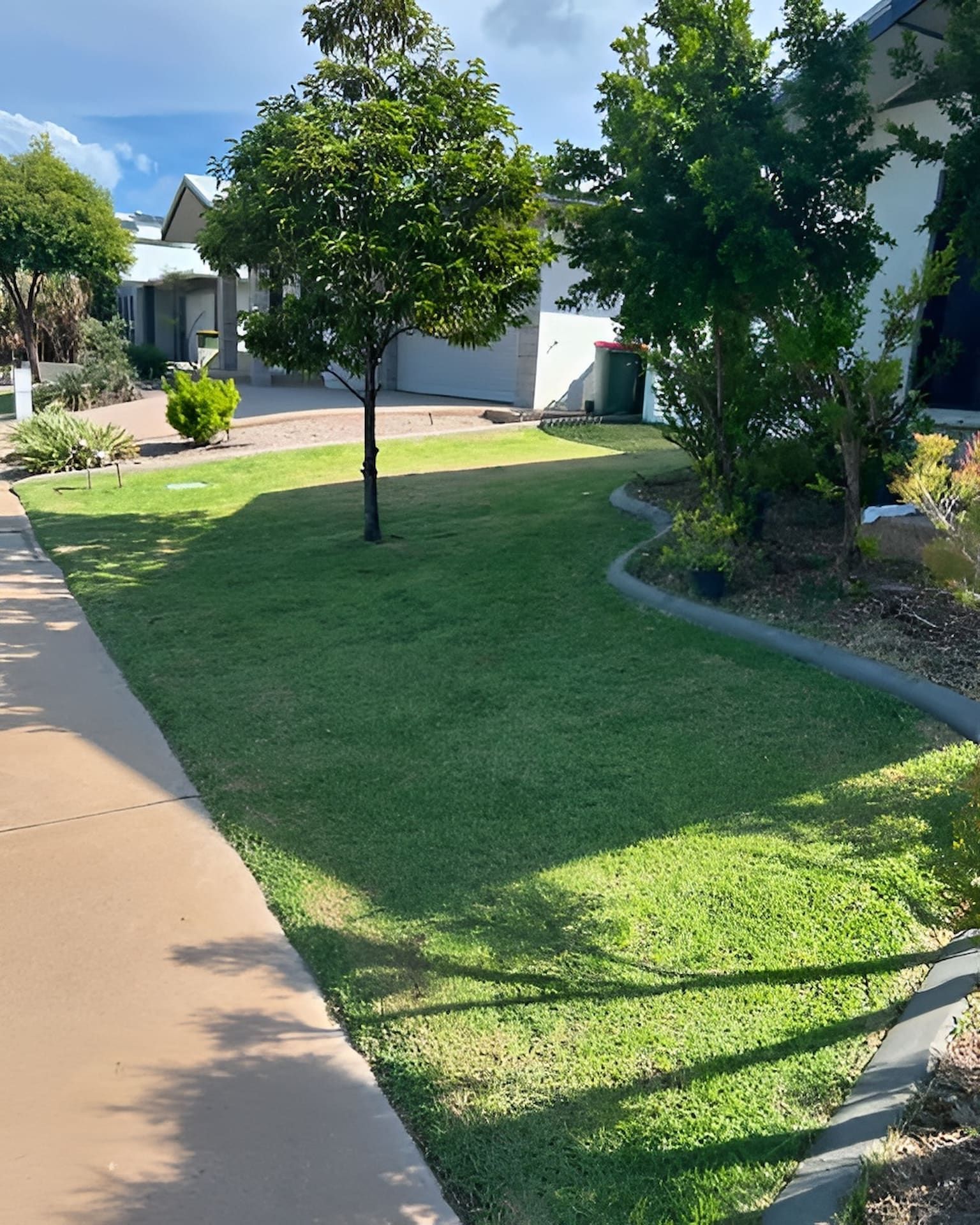 Lawn Mower in a Grassy Backyard Under a Bright Blue Sky With Puffy Clouds — Green Scene NT in Darwin, NT