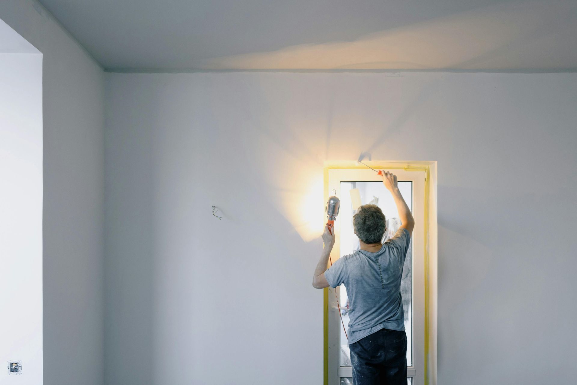 A man is standing in an empty room holding a light bulb.