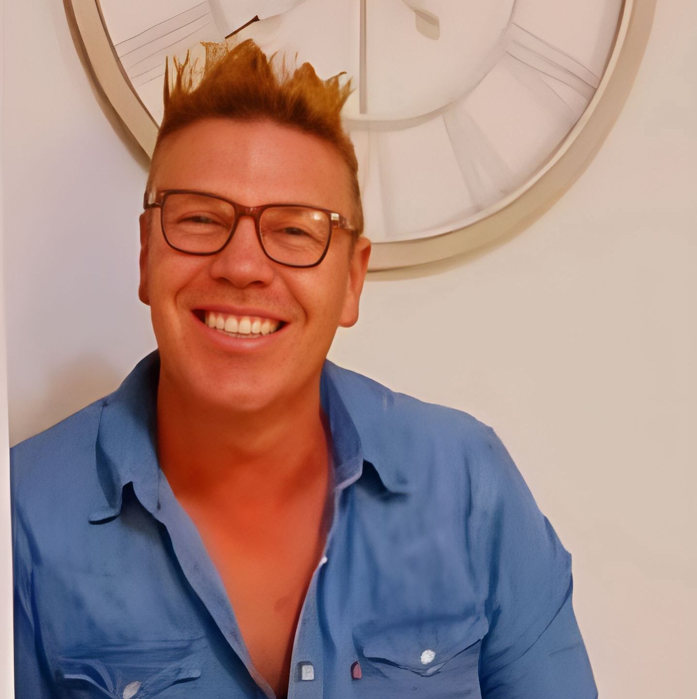 A Man Wearing Glasses And A Blue Shirt Is Smiling In Front Of A Clock — Kiwi Painter In Mooroobool, QLD