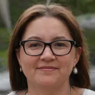 Una mujer que lleva gafas y pendientes sonríe para la cámara.