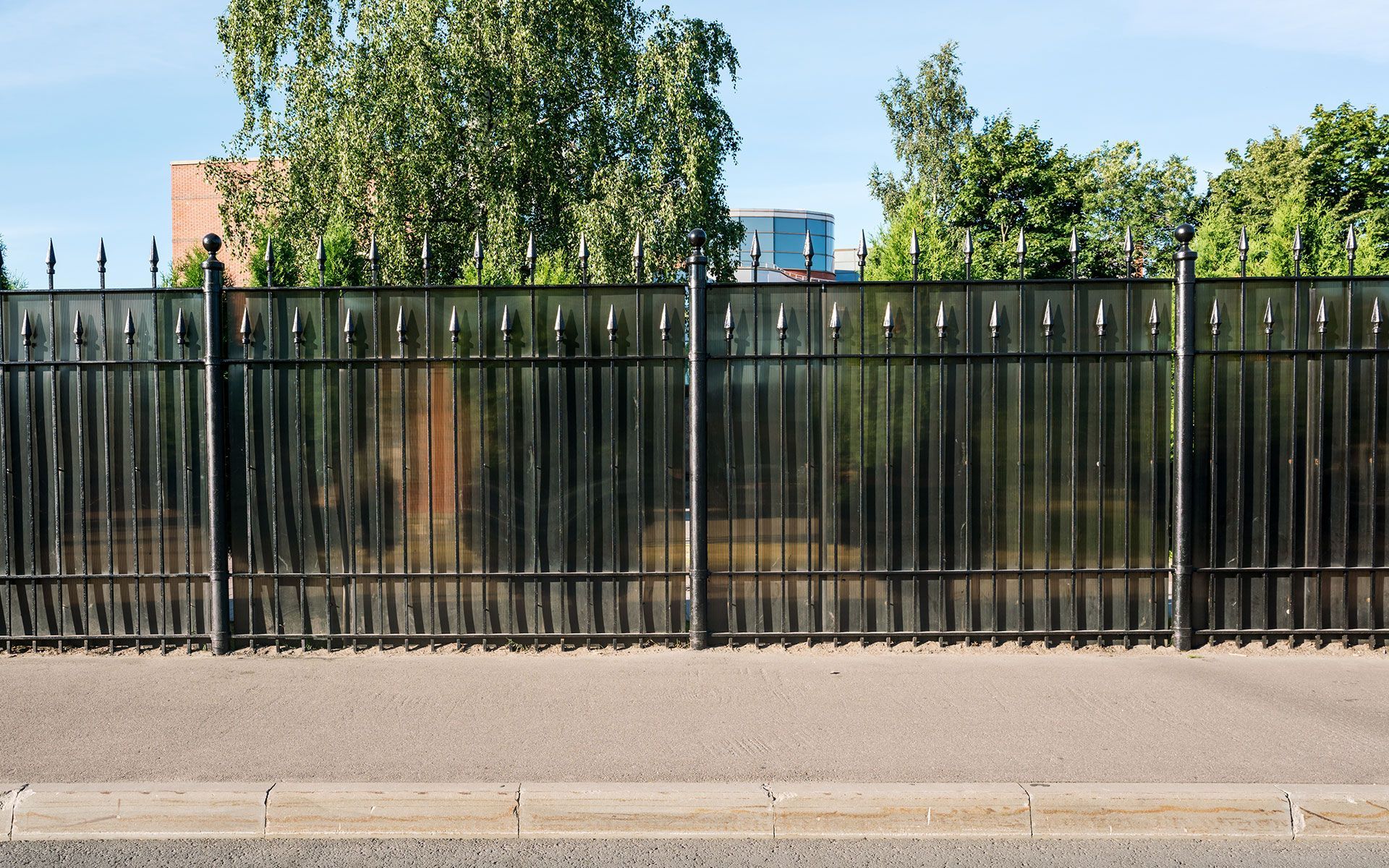 A black metal fence is along the side of a road.