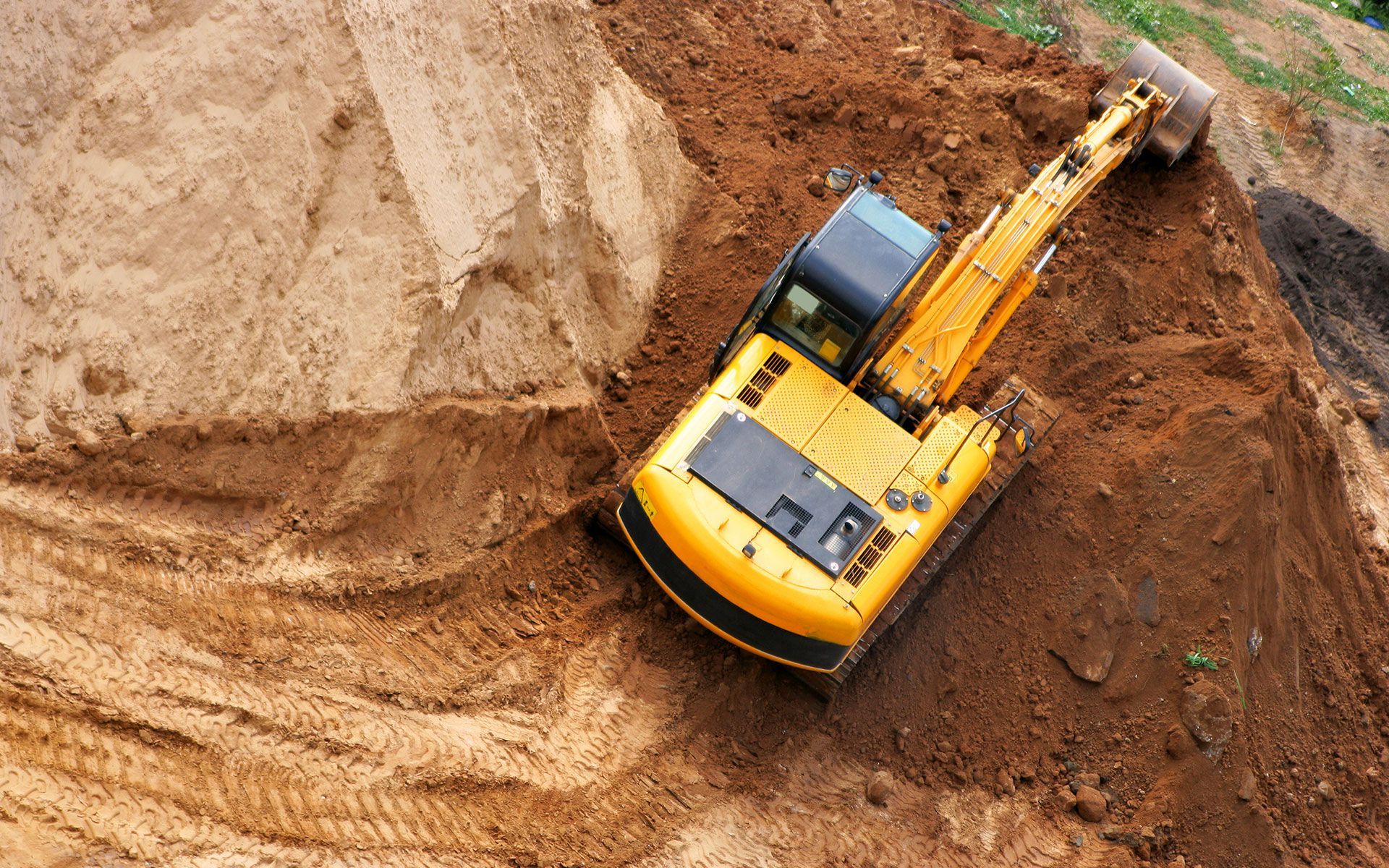 A yellow excavator is digging a hole in the dirt.