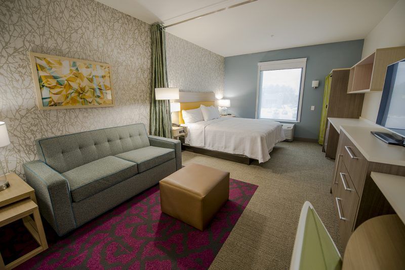 A hotel room with a couch , ottoman , desk and bed.