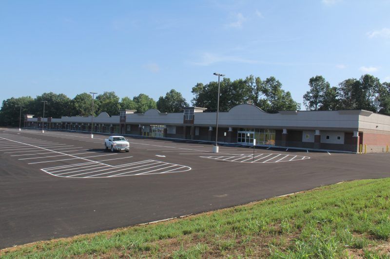 A white car is parked in front of a large building