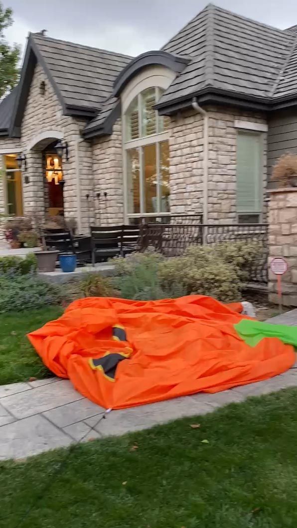 A large orange tent is sitting in front of a large brick house.