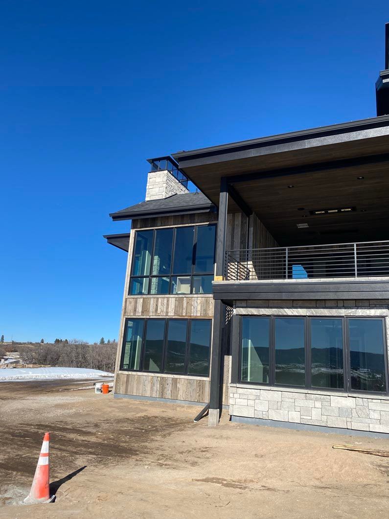 A large house with a lot of windows is sitting in the middle of a dirt field.