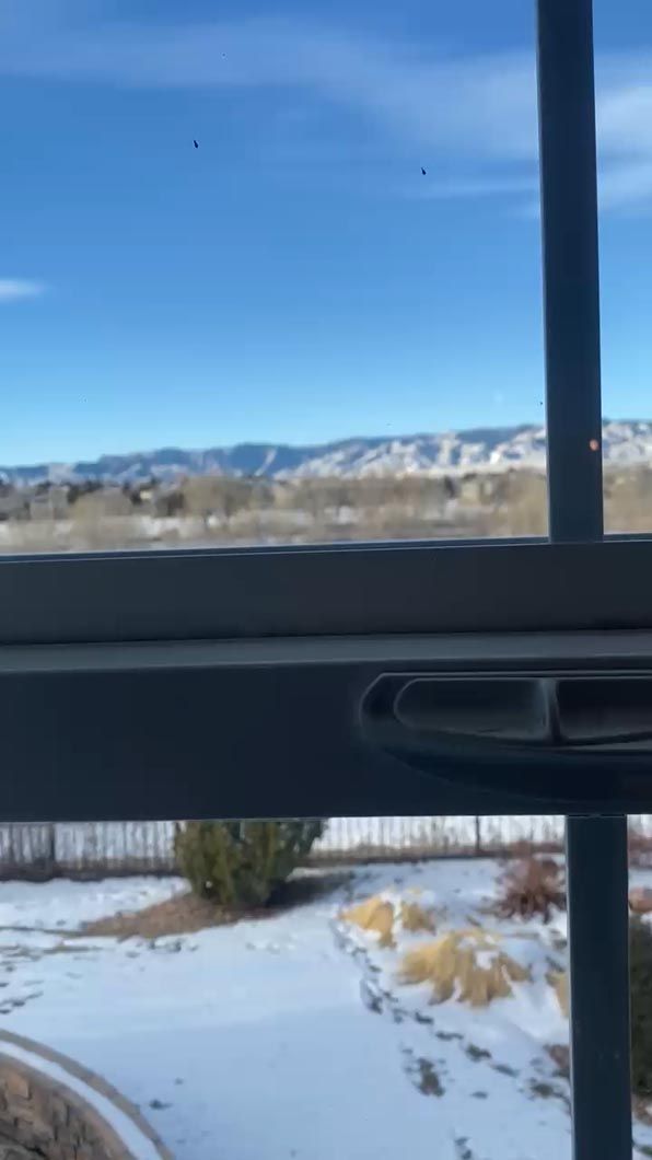 A window with a view of a snowy field and mountains