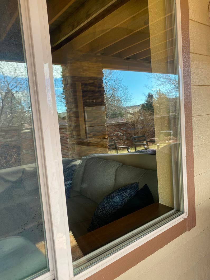 A living room with a couch and a table is reflected in a window.