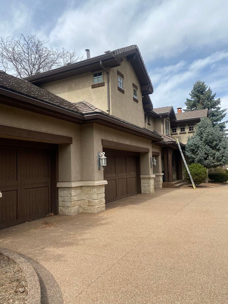 A large house with a lot of garage doors and a ladder in front of it.