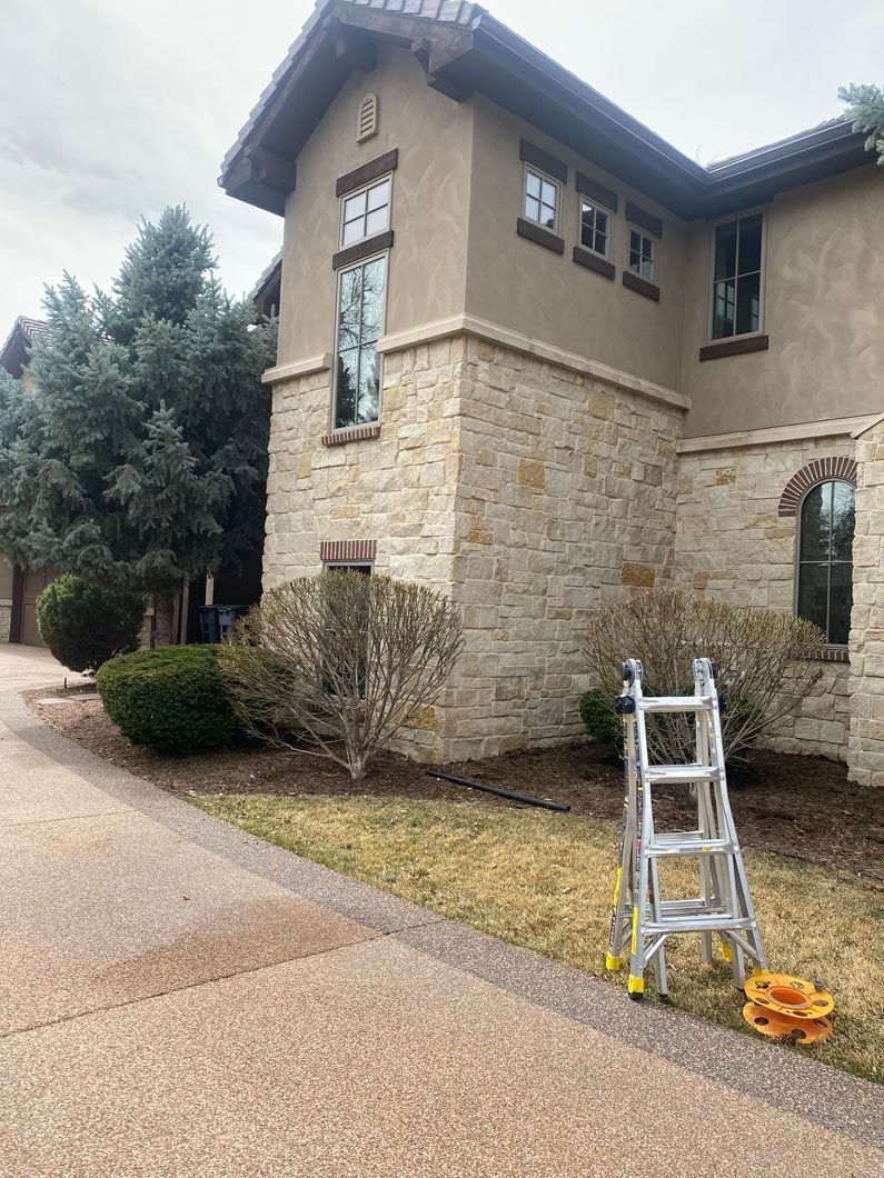 A ladder is sitting in front of a large house.