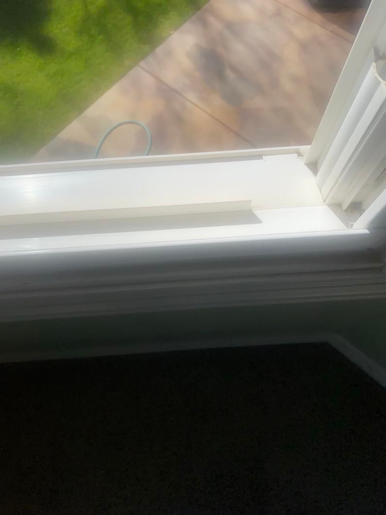 A close up of a window sill with a wooden floor in the background.