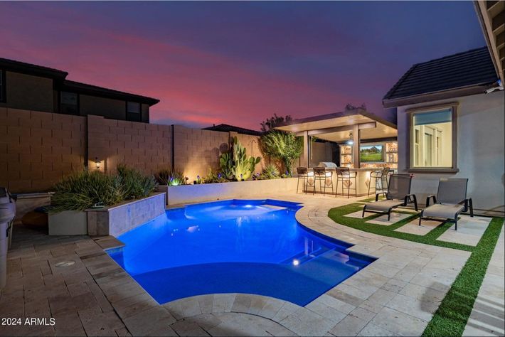 A large swimming pool is in the backyard of a house.