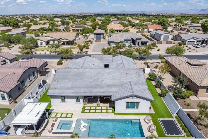 An aerial view of a house with a large swimming pool in the backyard.