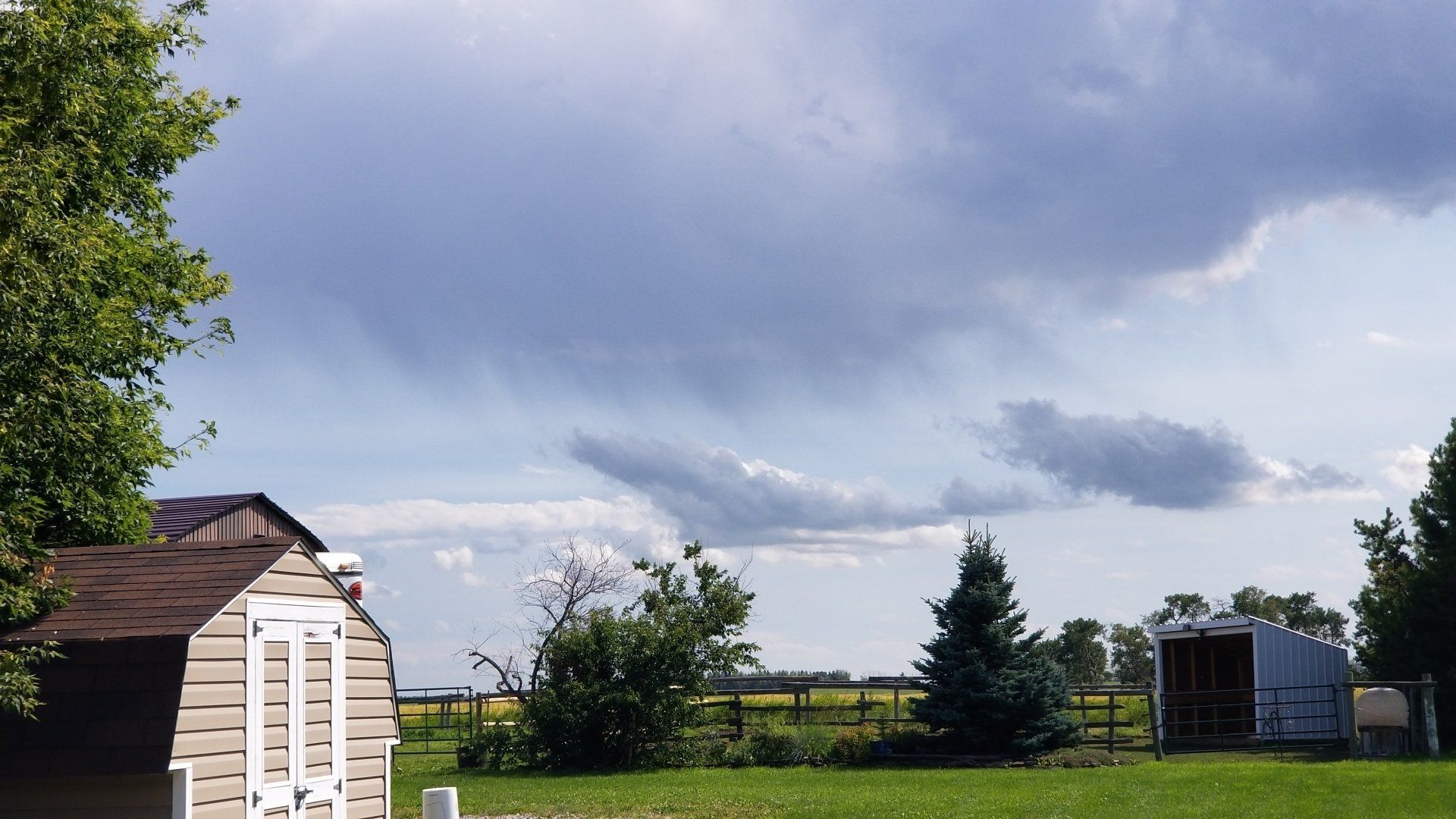 A shed in a field with a cloudy sky in the background