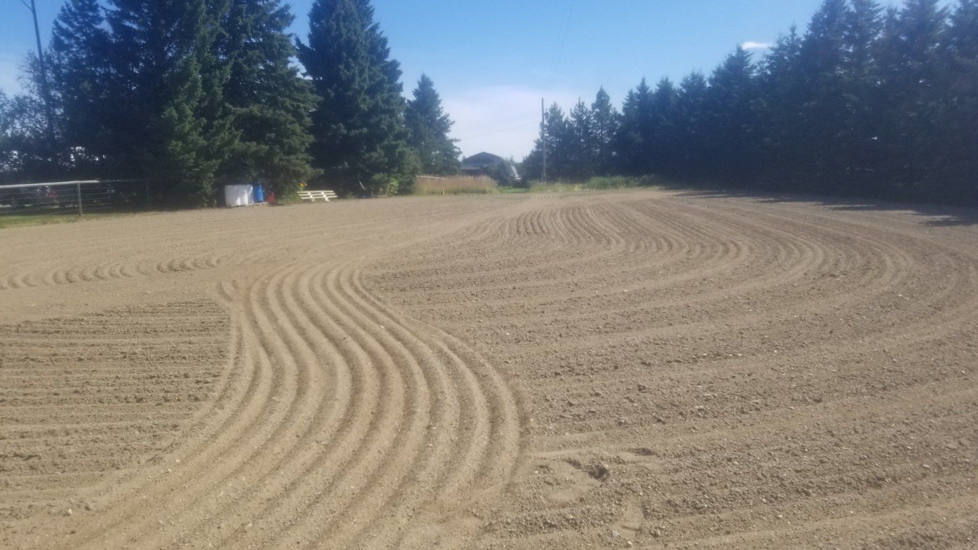 A large dirt field with trees in the background on a sunny day.